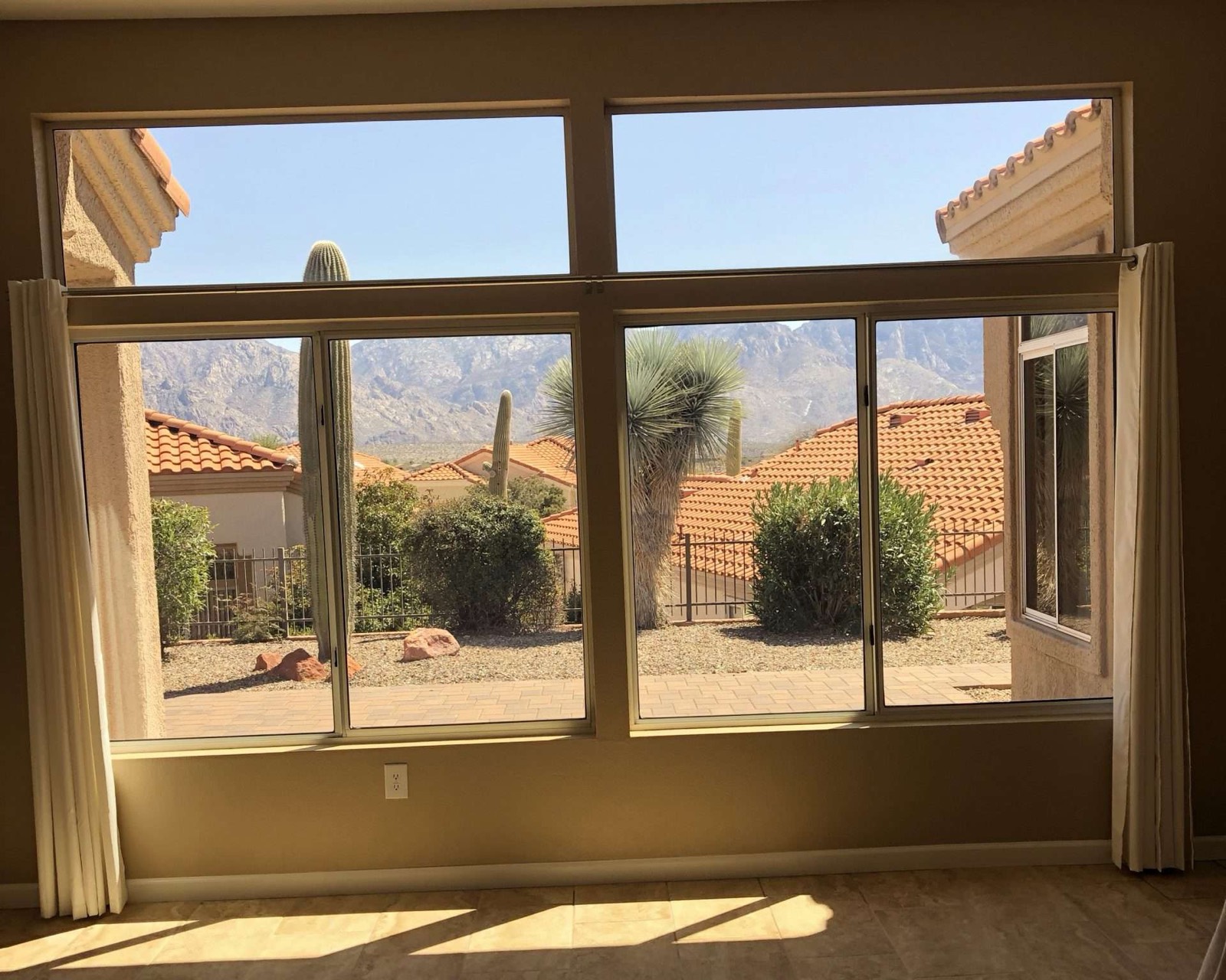 Great room with a wall of windows looking out to saguaros, tile roofs and the Santa Catalina Mountains
